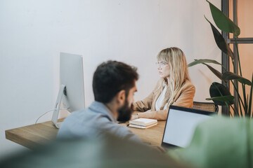 Partners working on a project on a wooden table in an industrial modern office, medium shot, de-focused on the foreground