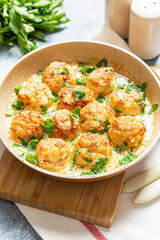 meatballs in white sauce in a frying pan on a gray background, comfortable homemade healthy food