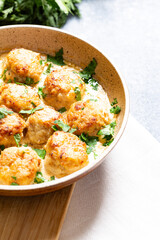 meatballs in white sauce in a frying pan on a gray background, comfortable homemade healthy food
