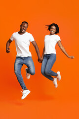 Fototapeta na wymiar Happy black lovers holding hands and jumping up