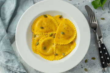 Homemade Pumpkin Ravioli with butter on a light concrete background. Top view