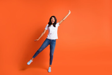 Fototapeta na wymiar Full length photo of lady hold empty space wear white t-shirt jeans footwear isolated orange color background