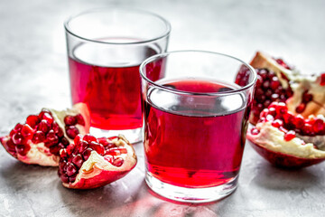 glass of pomegranate juice with fresh slices on stone background