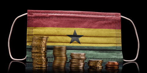 Medical mask with the flag of Ghana behind some shrinking stacks of various coins.(series)