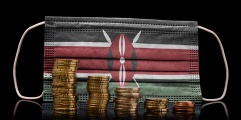 Medical mask with the flag of Kenya behind some shrinking stacks of various coins.(series)