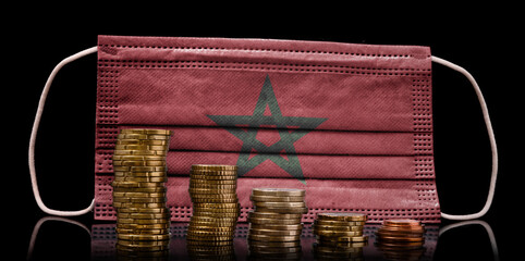 Medical mask with the flag of Morocco behind some shrinking stacks of various coins.(series)