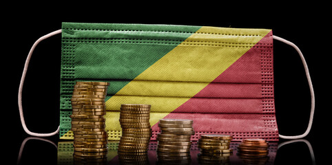Medical mask with the flag of Republic of the Congo behind some shrinking stacks of various coins.(series)