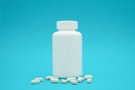 White bottle with pills isolated on blue background.
