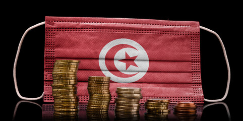 Medical mask with the flag of Tunisia behind some shrinking stacks of various coins.(series)