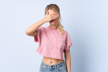 Blonde woman over isolated blue background covering eyes by hands. Do not want to see something