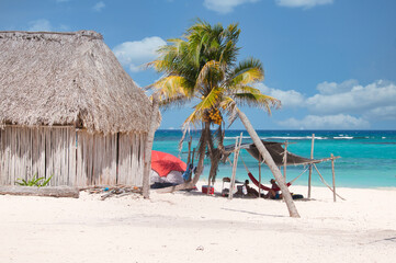 Free camping by the sea on a Caribbean beach in Mexico, in a rustic wooden hut near a palm tree. The ideal place to relax in contact with nature.