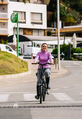 Plakat 40-year-old woman riding her electric bicycle through the streets of the city
