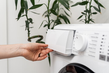 Woman washing laundry using modern automatic machine