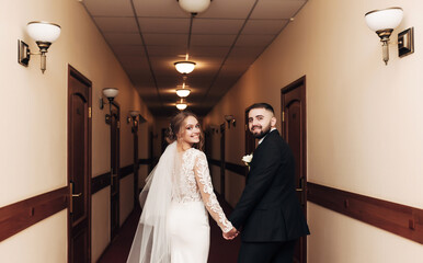 
the newlyweds are walking along the corridor of the hotel