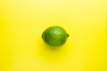 Fresh bright green lime on a yellow background.