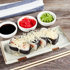 japanese sushi rolls in a rectangular plate on a light wooden table