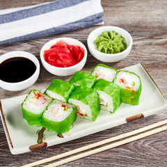 japanese sushi rolls in a rectangular plate on a light wooden table