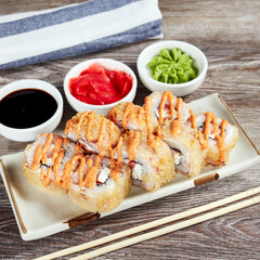 japanese sushi rolls in a rectangular plate on a light wooden table