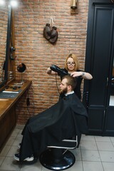 Professional hairdresser woman doing styling of handsome guy with electric hair clipper at barber shop