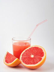 Fresh grapefruits and a glass of grapefruit juice on a white wooden background with a copy space. Close-up.