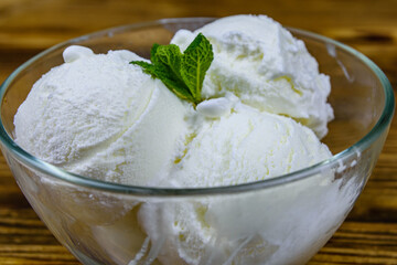 Glass bowl with ice cream balls and mint leaf on a wooden table