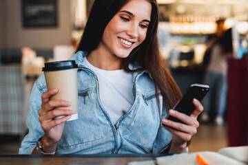 Attractive business woman sits at table in front of laptop and talks on mobile phone, negotiates on the phone. Beautiful brunette woman uses gadgets for work. Online training, remote work from home