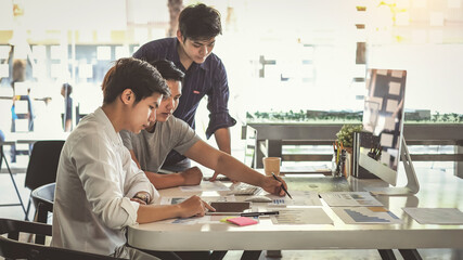 Young Asian businessman are meeting at working and pointing to analyzing charts and graphs.
