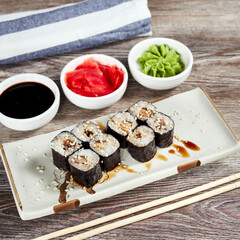 japanese sushi rolls in a rectangular plate on a light wooden table