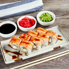 japanese sushi rolls in a rectangular plate on a light wooden table