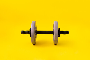 Obraz na płótnie Canvas a single grey weight dumbbell, sport body building equipment isolated on the color background