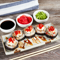japanese sushi rolls in a rectangular plate on a light wooden table