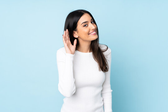 Young Caucasian Woman Isolated On Blue Background Listening To Something By Putting Hand On The Ear