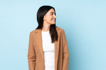 Young caucasian woman isolated on blue background looking to the side and smiling