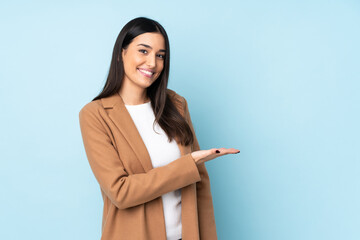 Young caucasian woman isolated on blue background presenting an idea while looking smiling towards