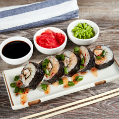 japanese sushi rolls in a rectangular plate on a light wooden table
