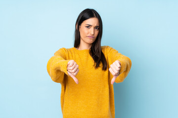 Young caucasian woman isolated on blue background showing thumb down with two hands
