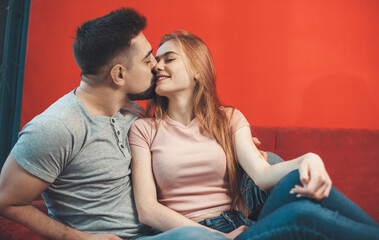 Couple kissing on a red couch celebrating valentines day together