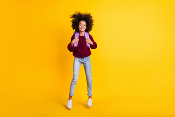 Fototapeta na wymiar Full body photo of cheerful dark skin kid jumping carry rucksack wear sweater isolated on yellow color background