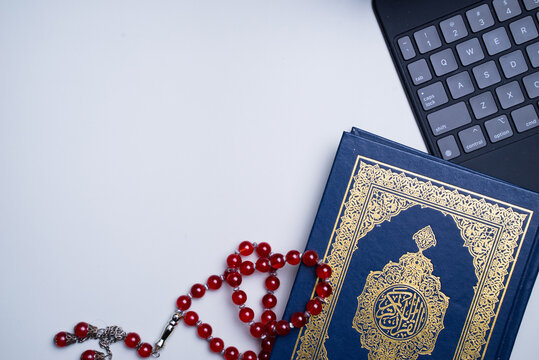 The application of technology devices and applications into digitization of Quran, or e-Quran. Online learning, or Quran recital using apps. Arabic words on the book means Holy Quran