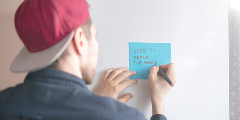 person write reminder text on the note sticker on the fridge