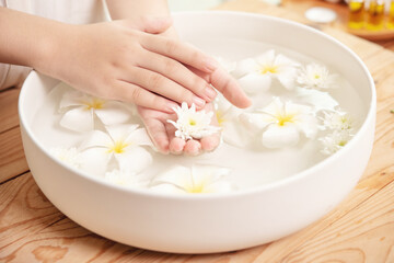Obraz na płótnie Canvas Spa treatment and product for female feet and hand spa. white flowers in ceramic bowl with water for aroma therapy at spa.