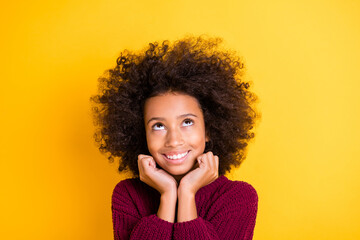Portrait of adorable dark skin girl arms under chin look up empty space wear knitted isolated on yellow color background
