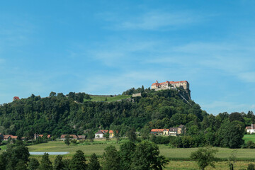 Fototapeta na wymiar A distant view on the Riegersburg castle in Austria towering above the area. Clear blue sky above the castle. The massive fortress was build on the rock. Defensive structure from the middle ages. Calm