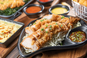 Crispy fried pork, tonkatsu, fried pork belly with sauce in black dishon wooden table. Food concept.
