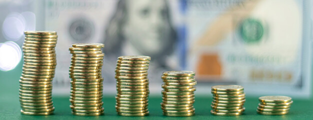 Banner with stacks of gold money coin on blur hundred dollar background with copy space. Concept of saving money.