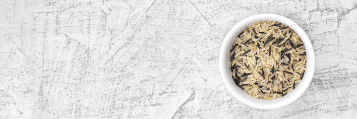 Banner withmixed rice in white plate on white stone background. Vegetarian superfood. Mixed rice grains. Top view with copy space. White and black rice.