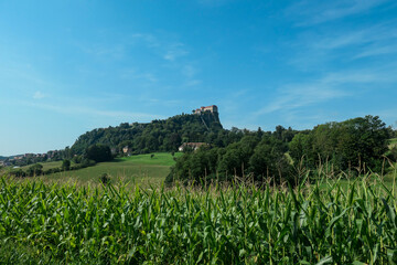 Fototapeta na wymiar Riegersburg castle in Austria towering above the area. There are mais crops ripening on the field in front. Clear blue sky above the castle. The massive fortress was build on the rock. Middle ages