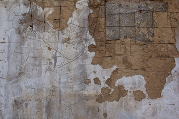 An old wall with crumbling plaster and a metal mesh sticking out.