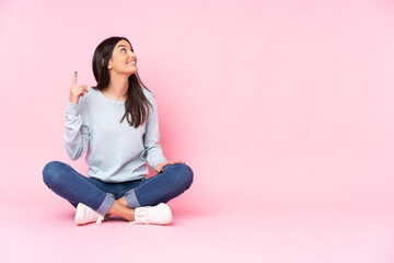 Young caucasian woman isolated on pink background pointing up and surprised