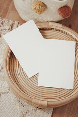 White invitation cards in a wooden wicker basket in boho style